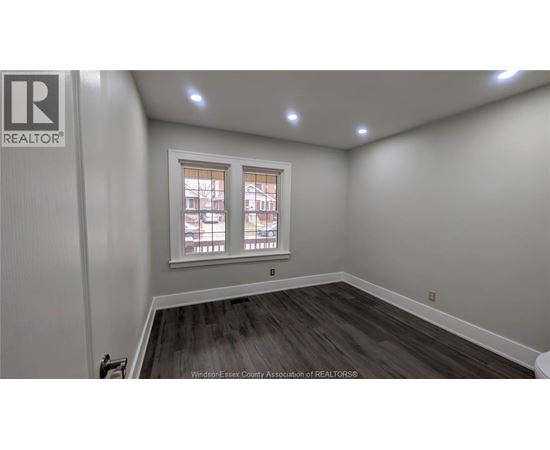 A room with a window and a wooden floor.