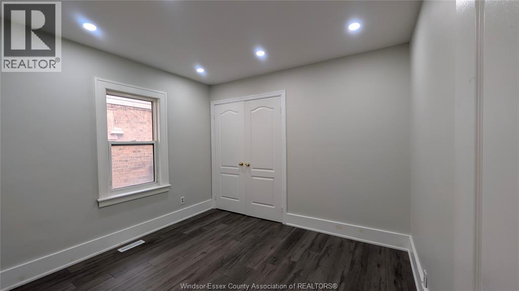 A room with a white door and a window with a view of a brick building outside.