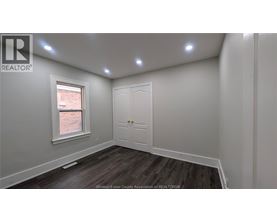 A room with a white door and a window with a view of a brick building outside.