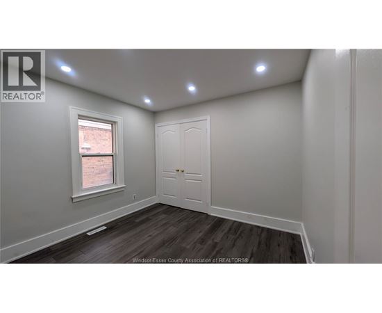 A room with a white door and a window with a view of a brick building outside.