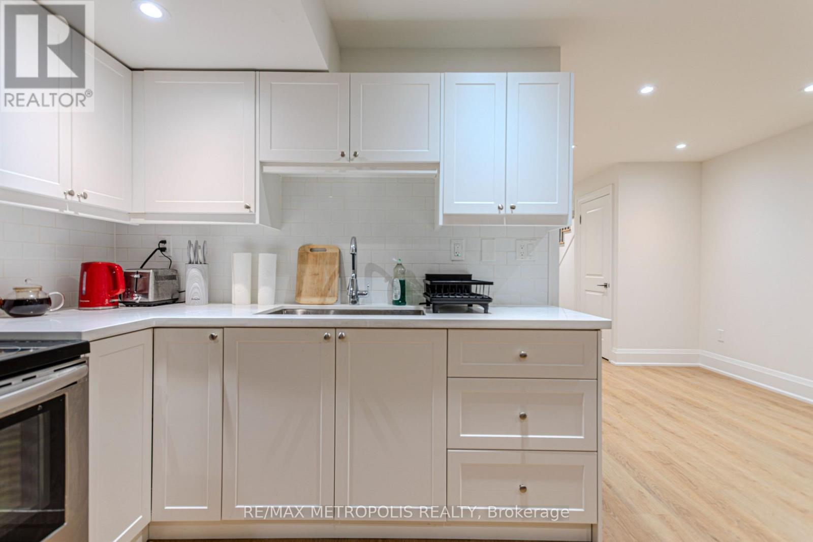 A kitchen with white cabinets and a wooden cutting board on the counter.