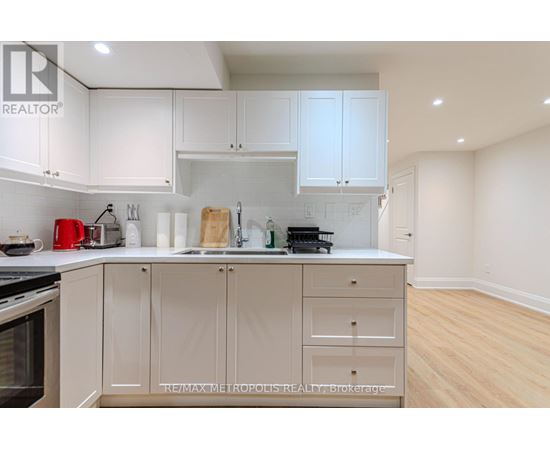 A kitchen with white cabinets and a wooden cutting board on the counter.