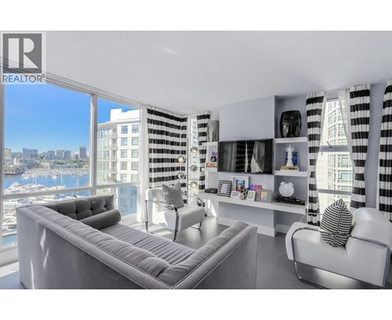 A living room with a grey sofa and a view of the city.