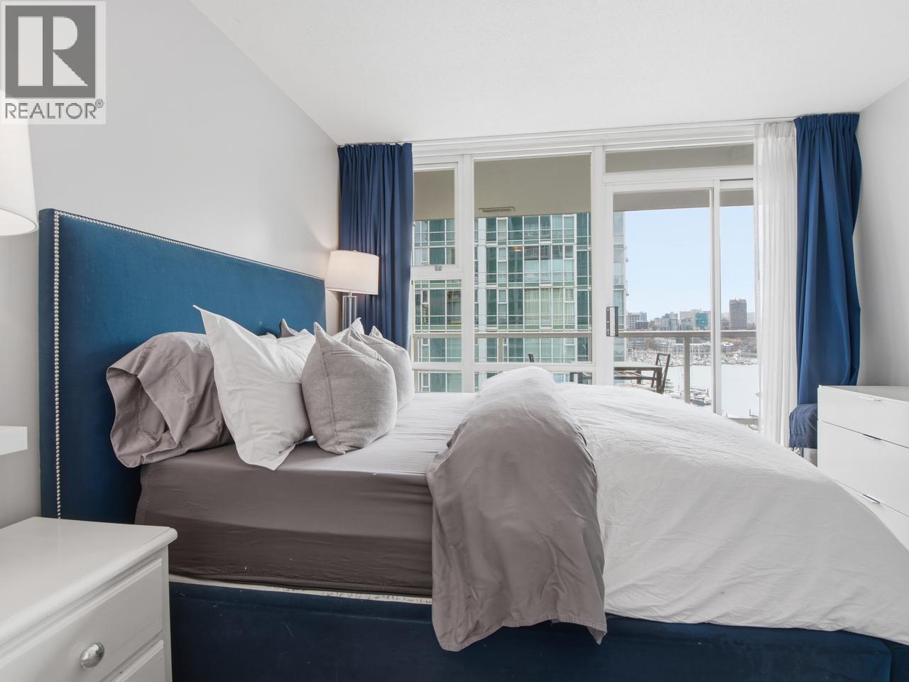A bedroom with a large bed and a window overlooking a cityscape.