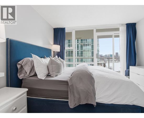 A bedroom with a large bed and a window overlooking a cityscape.