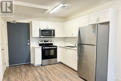 A kitchen with white cabinets and a stainless steel refrigerator.