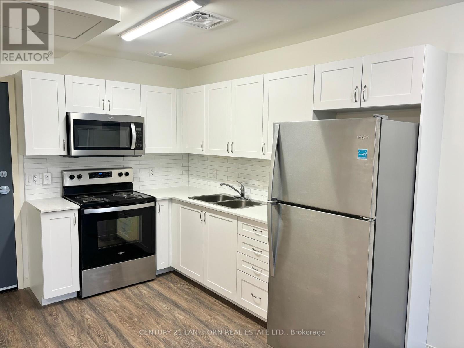 A kitchen with white cabinets and a stainless steel refrigerator.