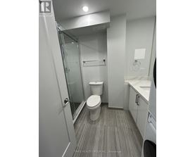 A bathroom with a toilet, sink, and mirror.