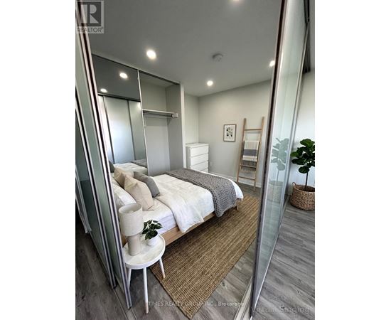 A bedroom with a bed, a chair, and a mirror.