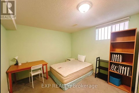 A bedroom with a bed, desk, and bookshelf.