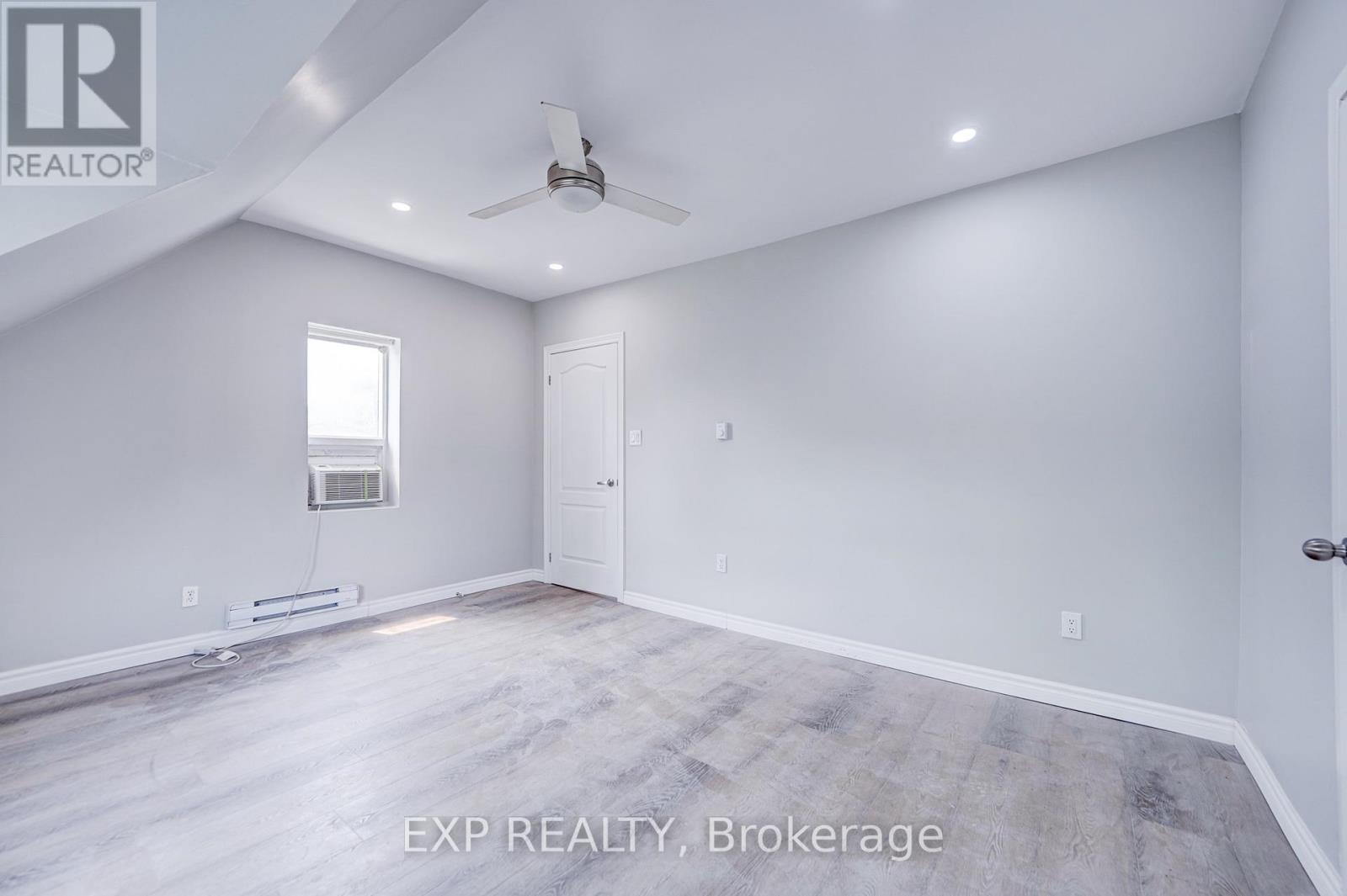 A spacious room with a ceiling fan and a window.