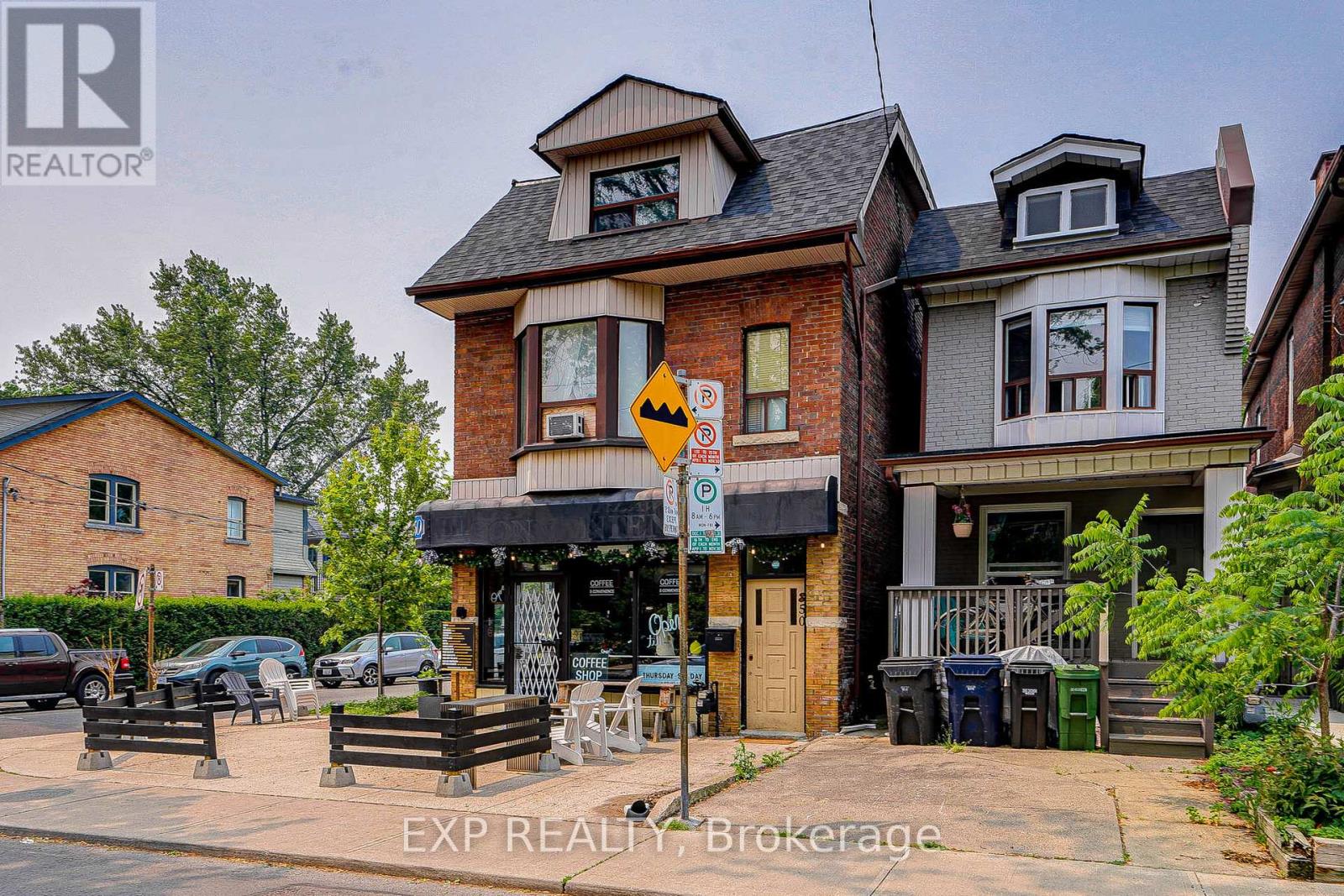 A real estate sign is displayed in front of a two-story house.
