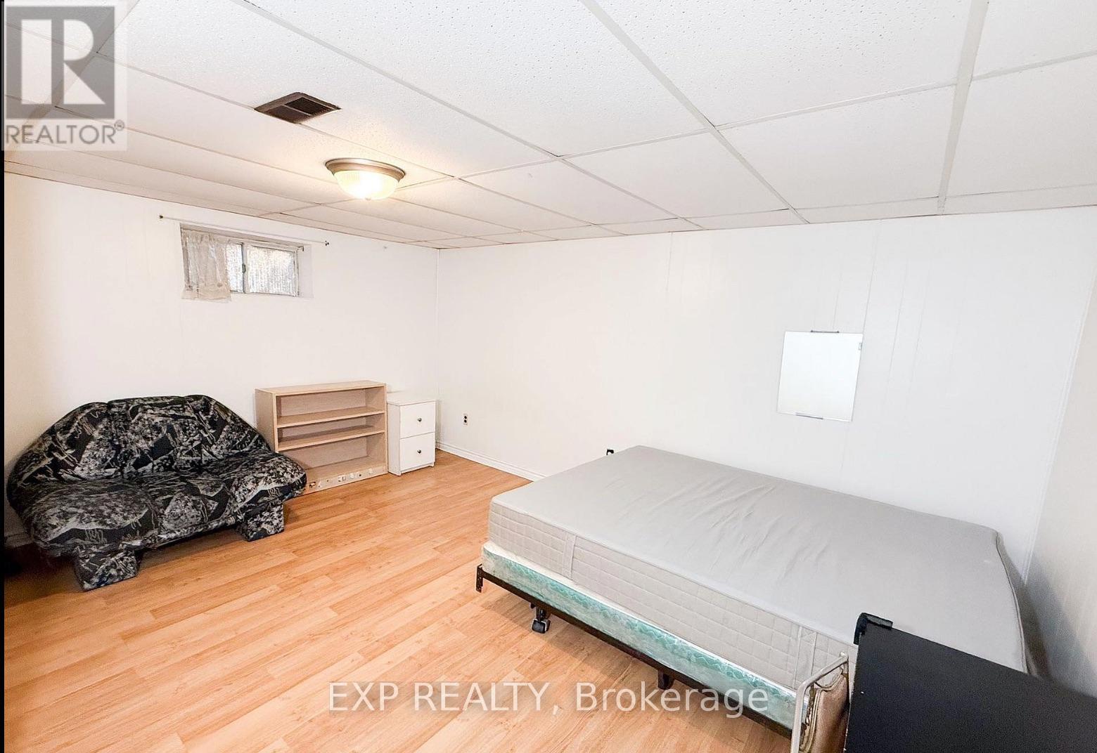 A bedroom with a bed, dresser, and a couch.