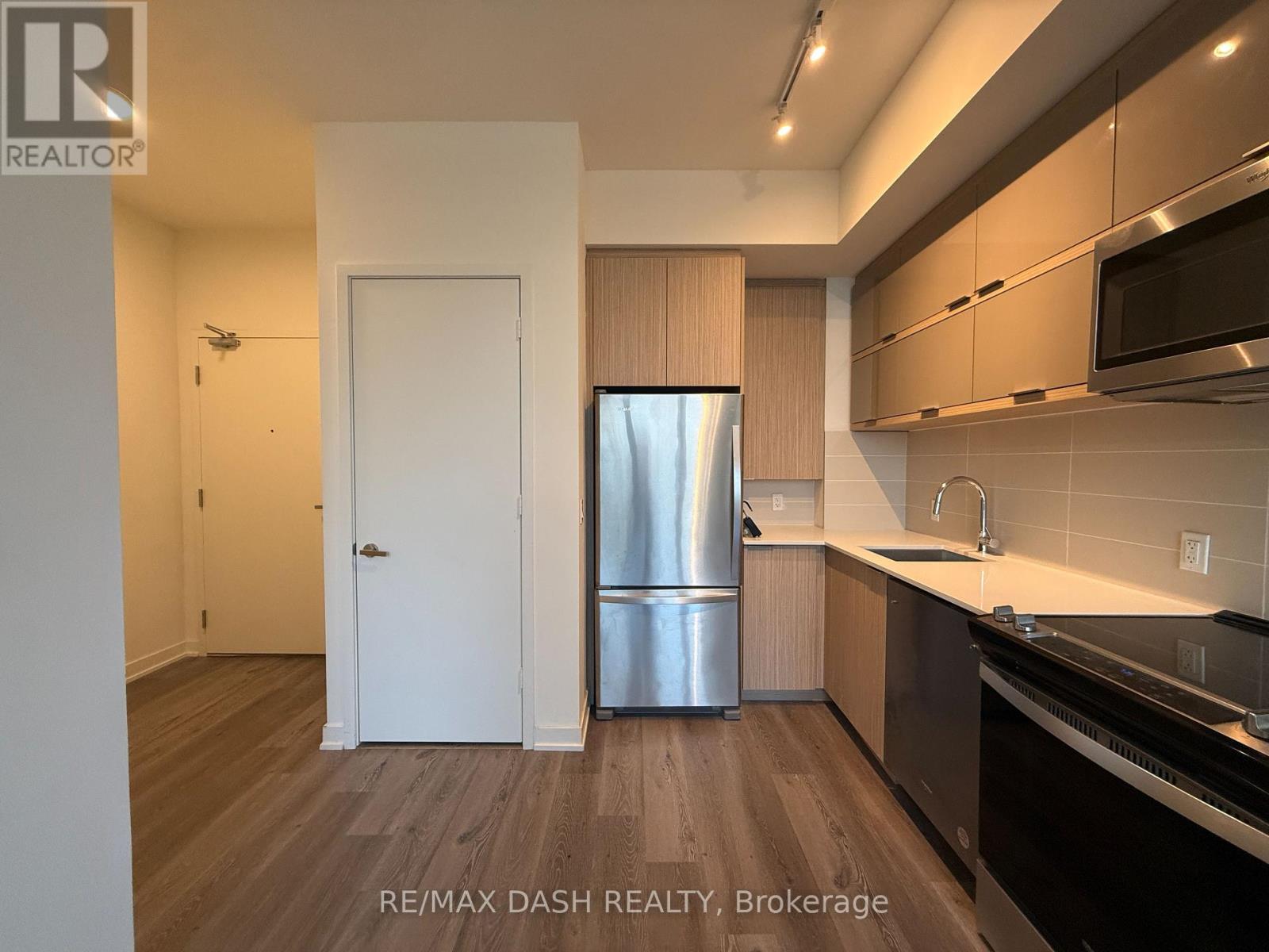 A kitchen with a refrigerator, sink, and cabinets.