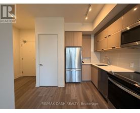 A kitchen with a refrigerator, sink, and cabinets.