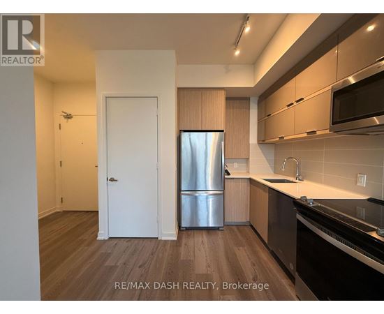 A kitchen with a refrigerator, sink, and cabinets.