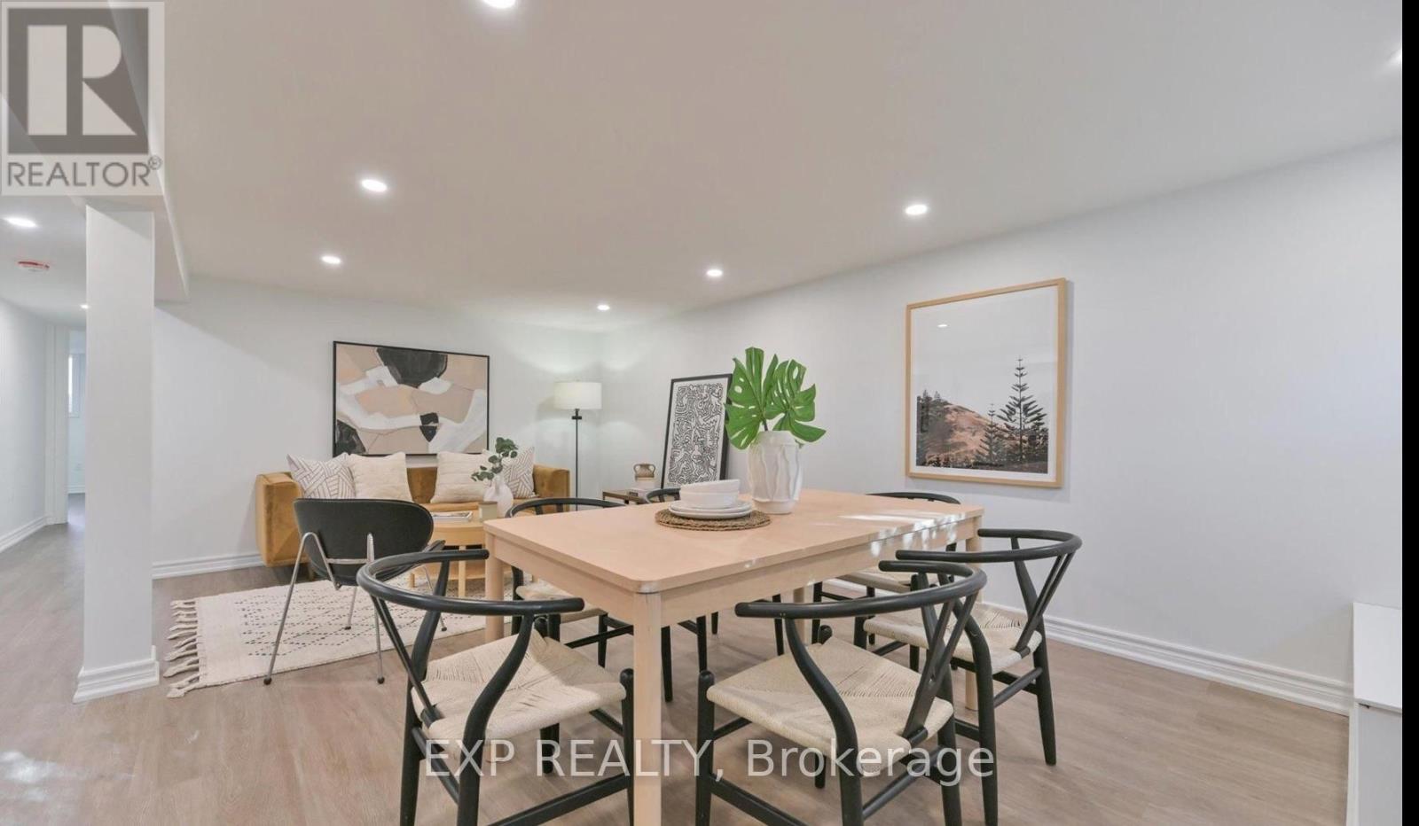 A dining room with a table set for four and a framed picture on the wall.