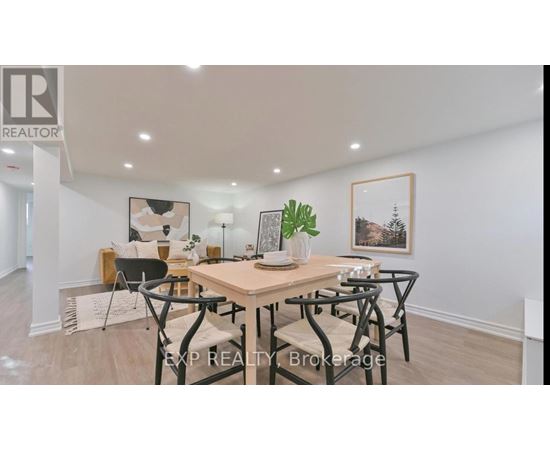 A dining room with a table set for four and a framed picture on the wall.