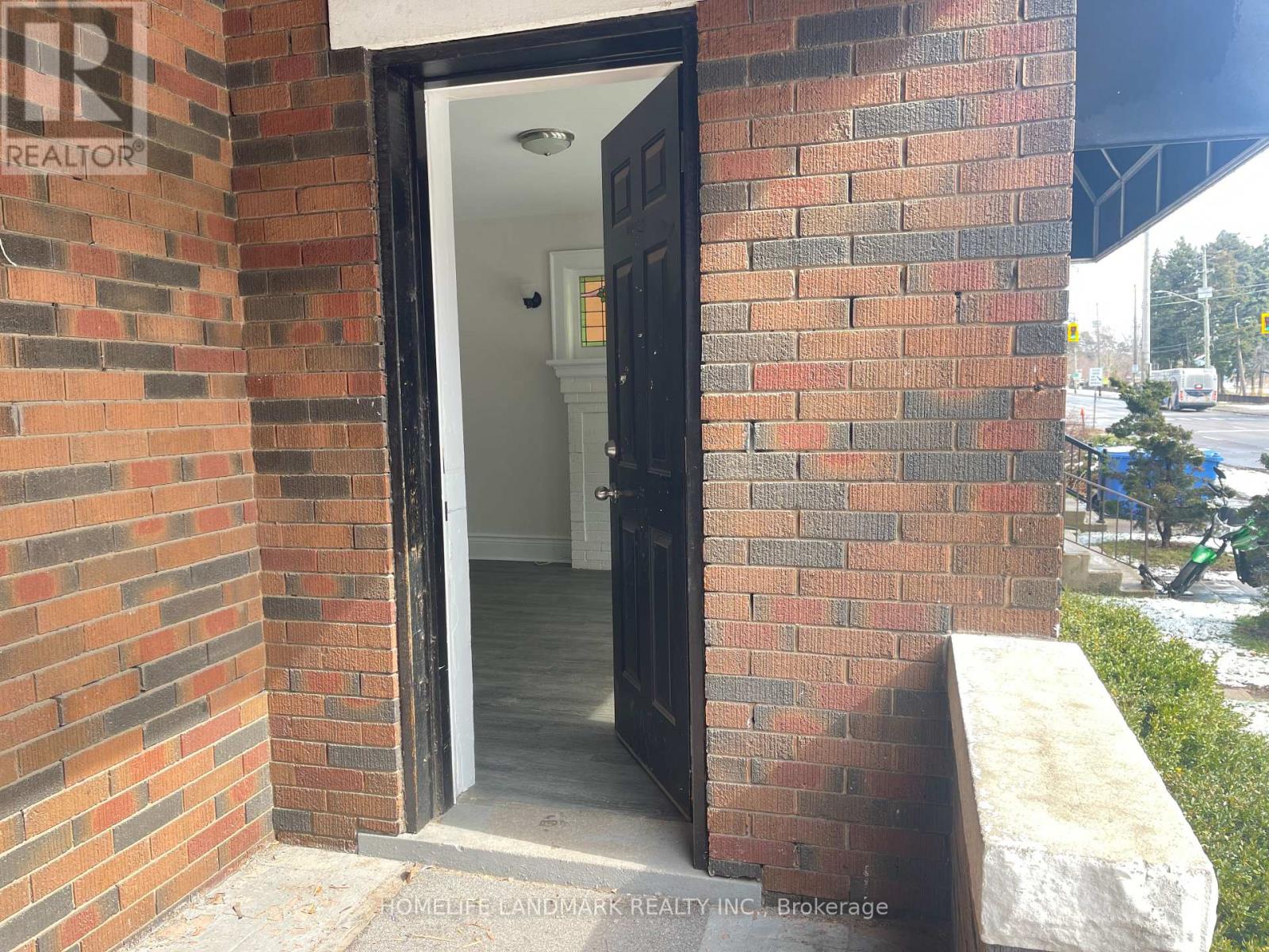 A brick wall with a doorway leading to a white interior.