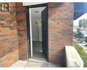 A brick wall with a doorway leading to a white interior.