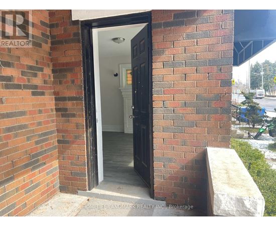 A brick wall with a doorway leading to a white interior.