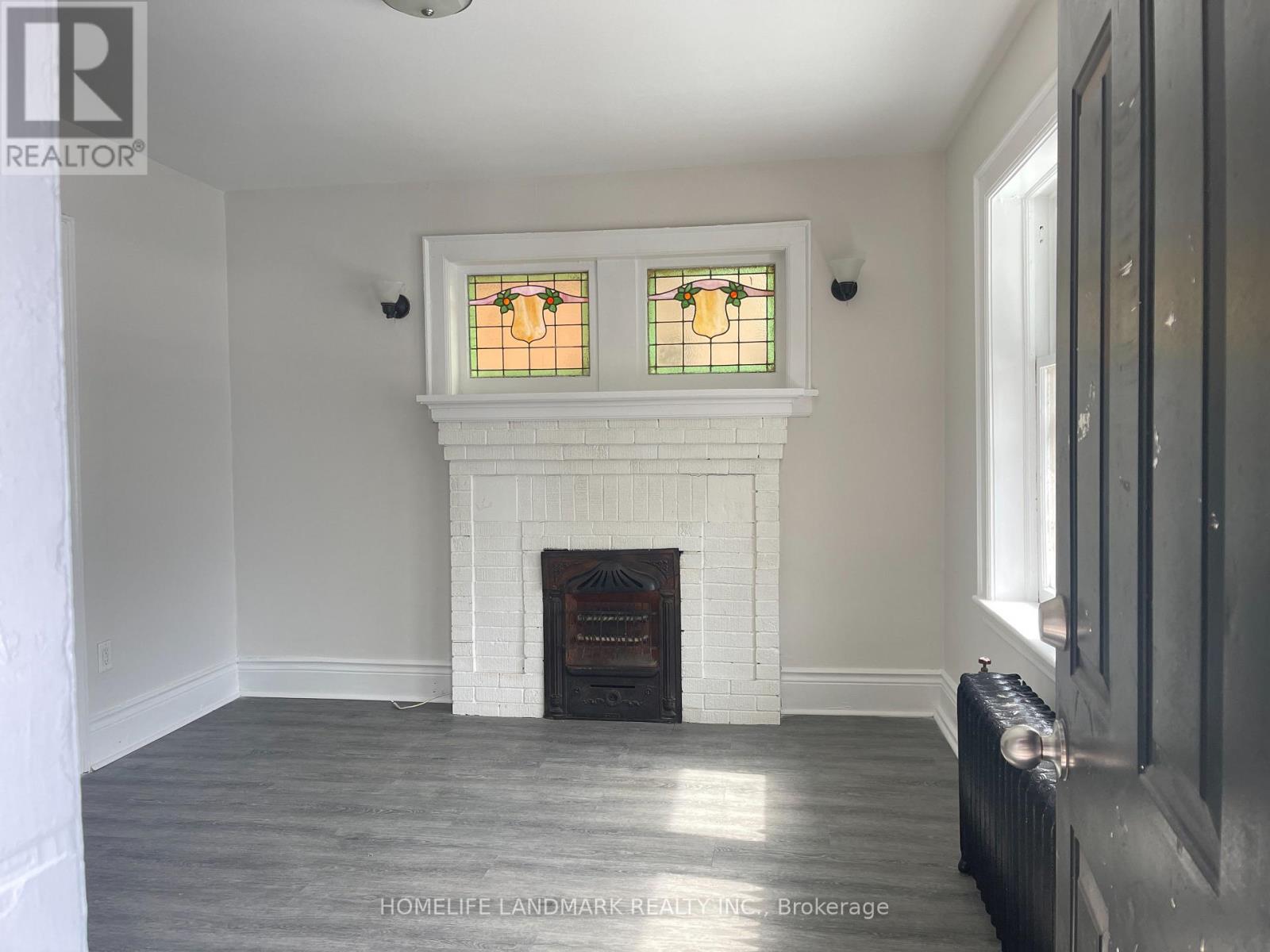 A white fireplace with a stained glass window above it.