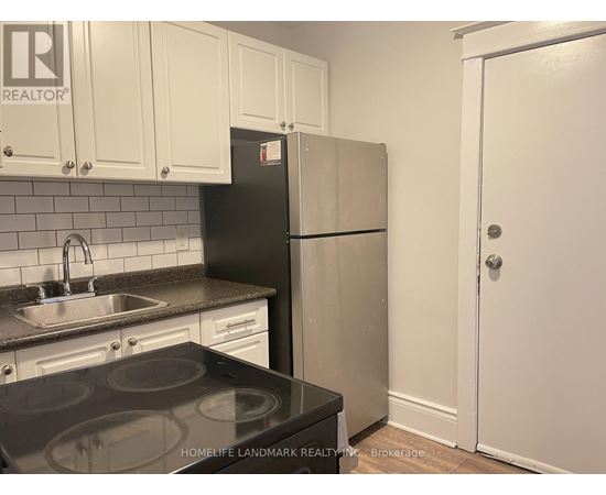 A kitchen with a black stove top and a white refrigerator.