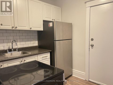 A kitchen with a black stove top and a white refrigerator.