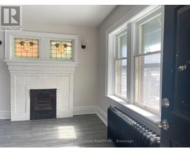 A room with a fireplace and a window with a stained glass design.