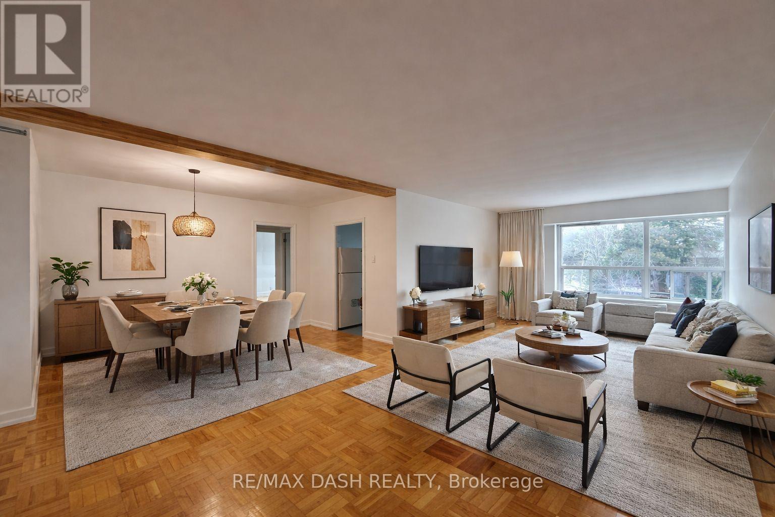 A well-lit, spacious living room with a dining area and a television.