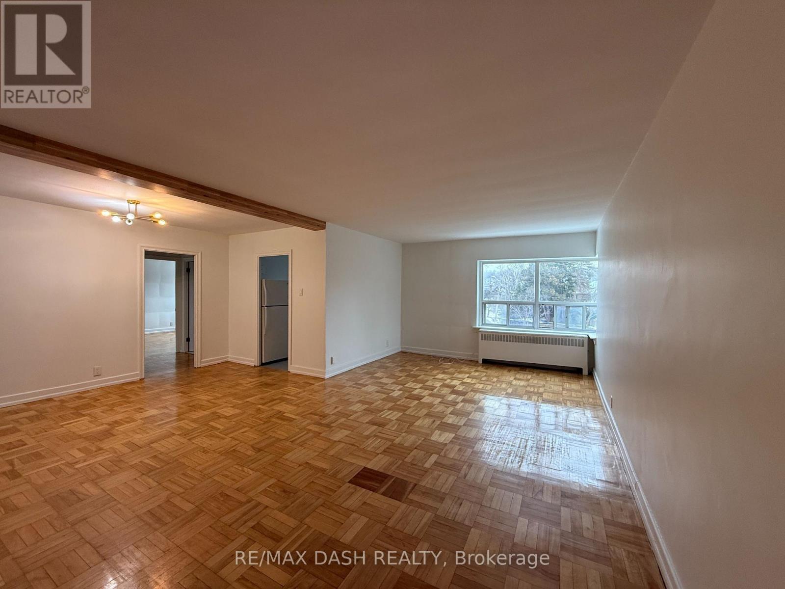 A room with wooden flooring and a window with a view of trees outside.