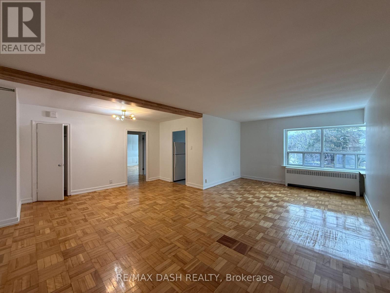 A spacious room with wooden flooring and a large window.