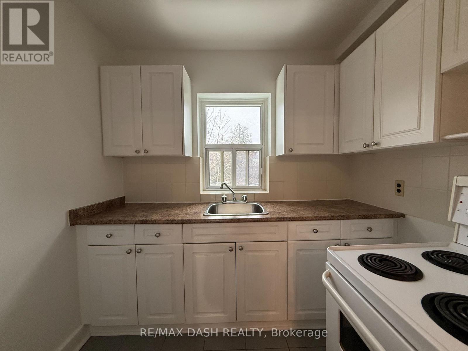 A kitchen with white cabinets and a marble countertop.