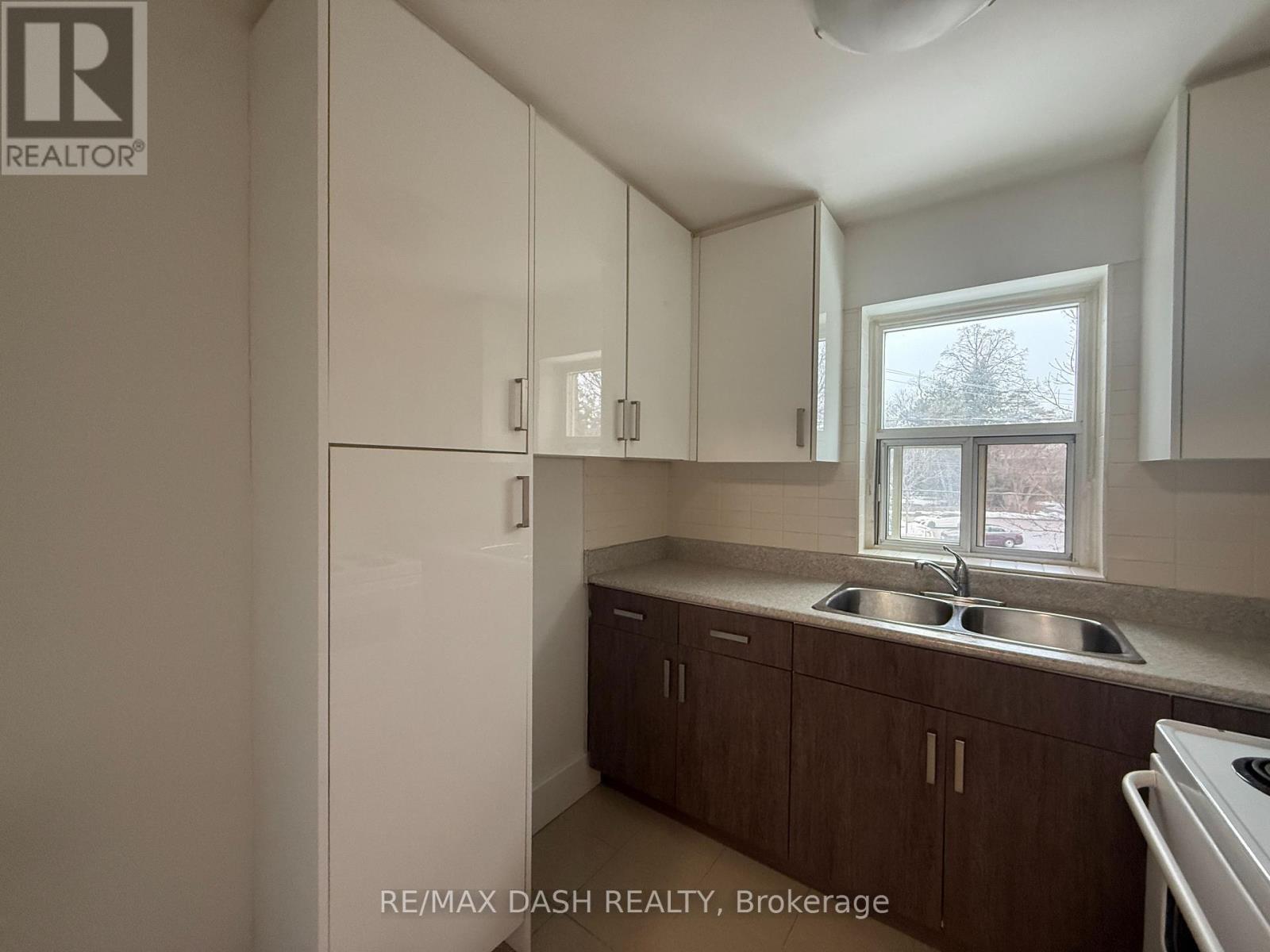 A kitchen with white cabinets and a window.