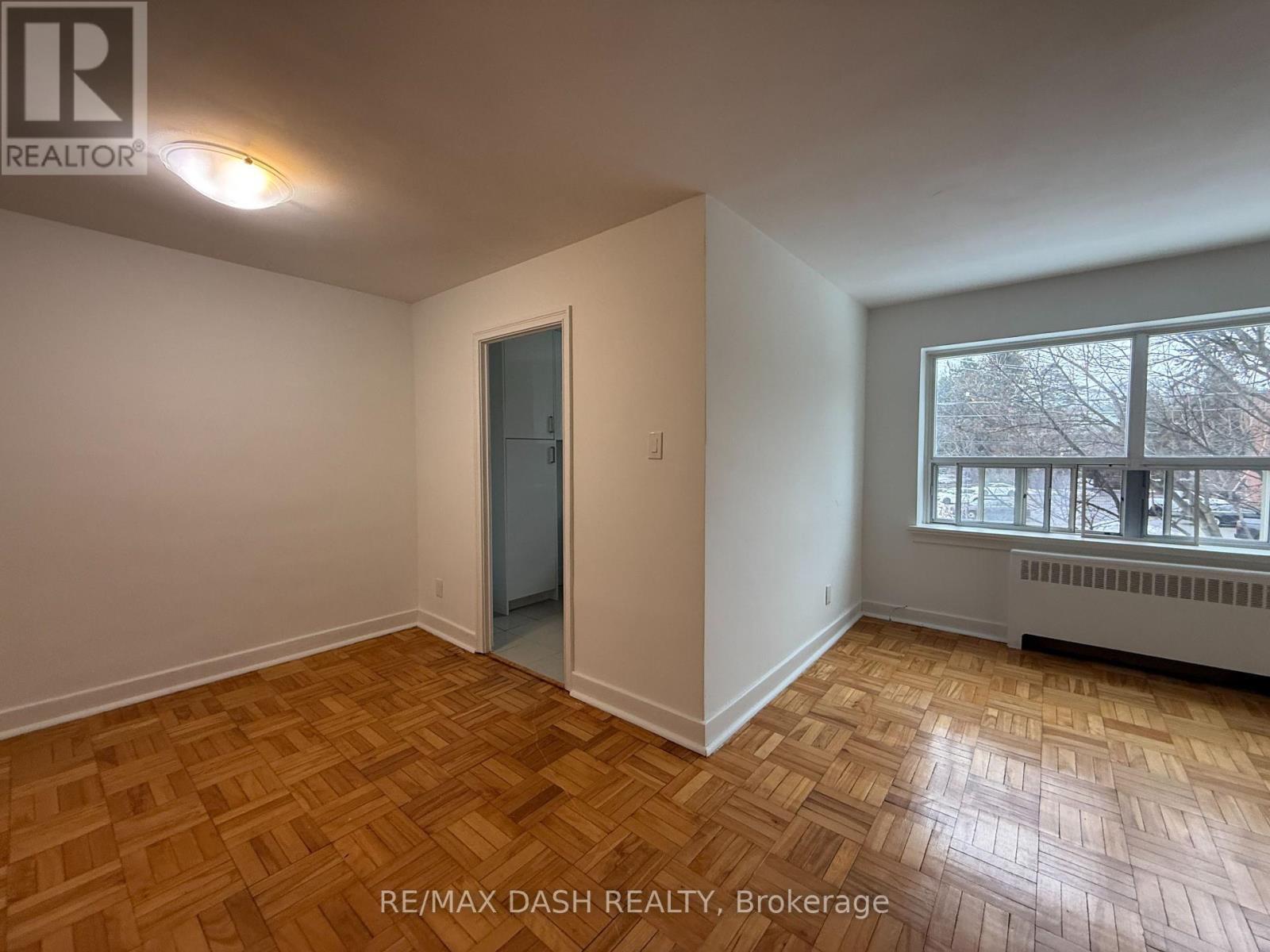 A room with a wooden floor and a window with a view of trees outside.