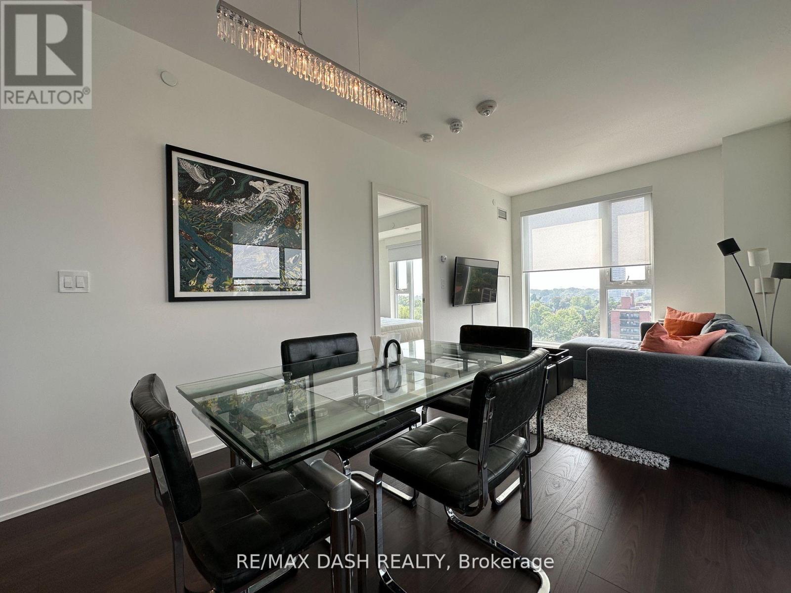 A modern living room with a glass dining table and black chairs.
