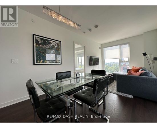 A modern living room with a glass dining table and black chairs.