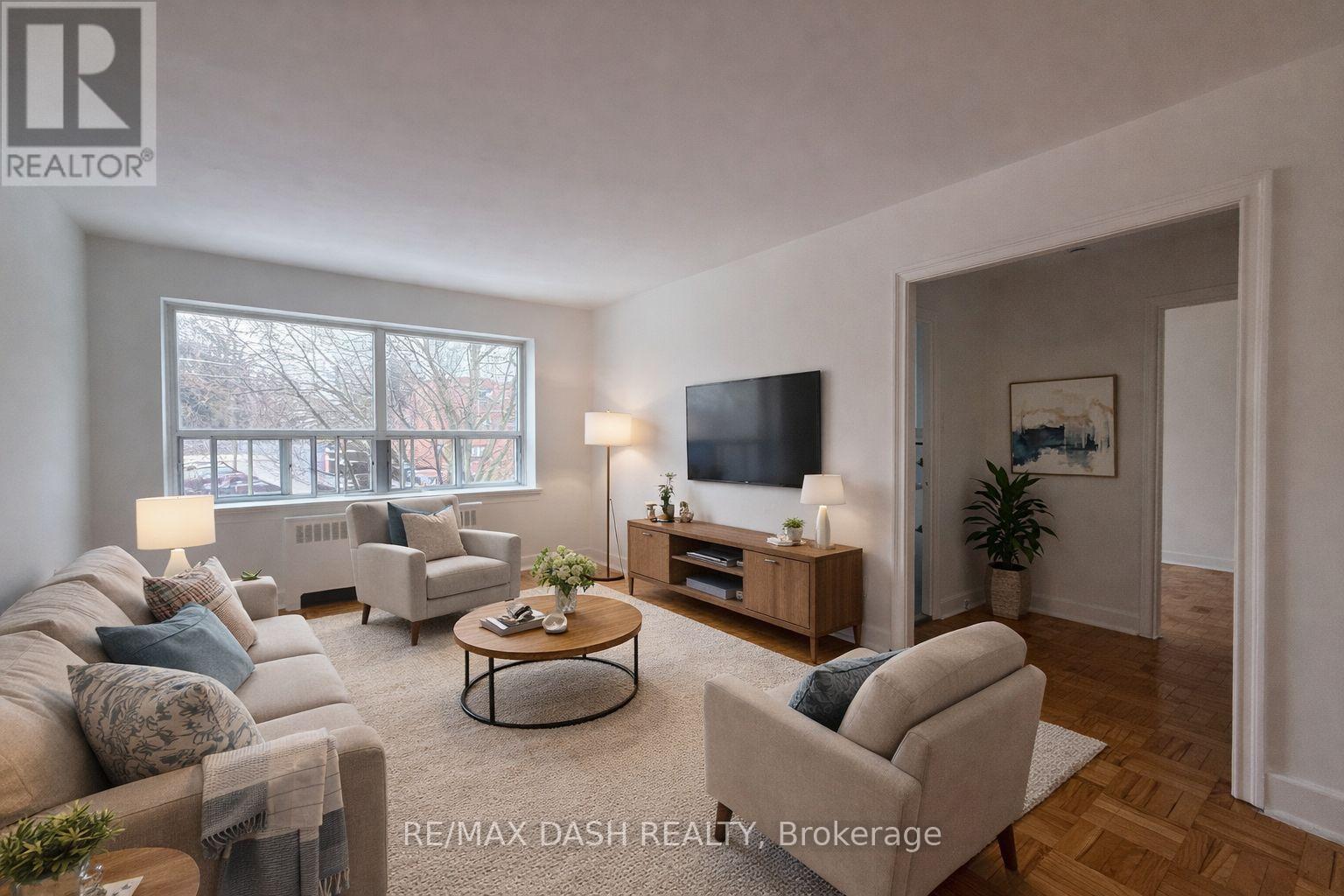 A well-lit living room with a couch, chair, and television.