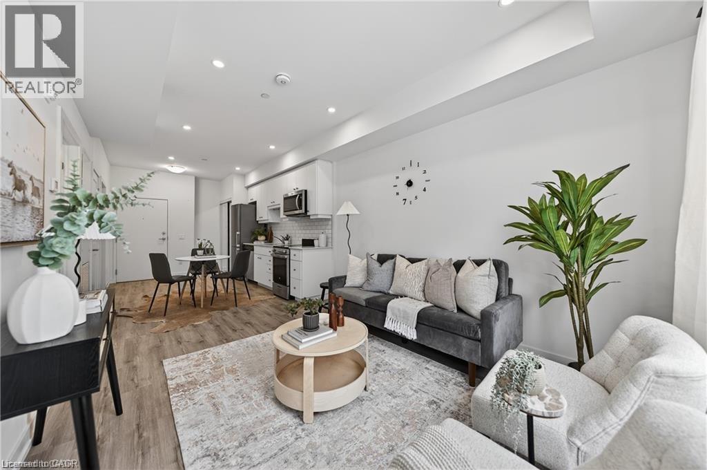 A modern living room with a grey sofa, a coffee table, and a dining table set up.