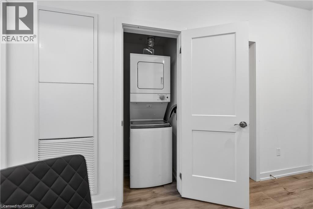 A small white refrigerator is in a narrow space between two doors.