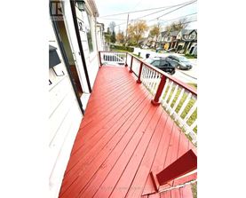 A red wooden deck with a white railing.