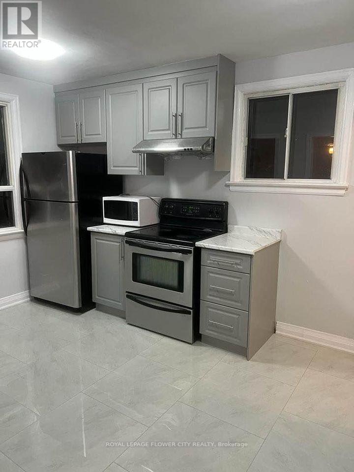 A kitchen with a refrigerator, microwave, oven, and cabinets.