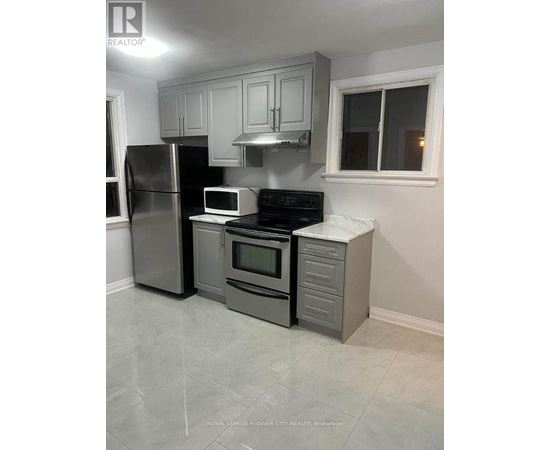 A kitchen with a refrigerator, microwave, oven, and cabinets.