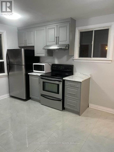 A kitchen with a refrigerator, microwave, oven, and cabinets.