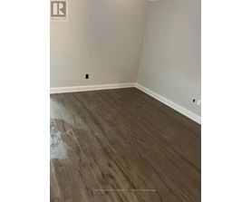 A room with wooden flooring and a white wall.