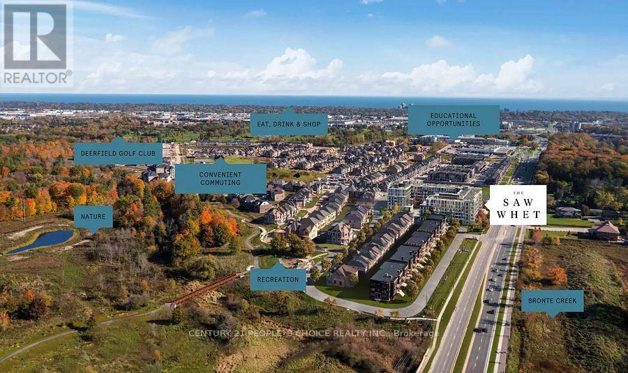 An aerial view of a real estate development with a road and buildings, surrounded by trees and a body of water.
