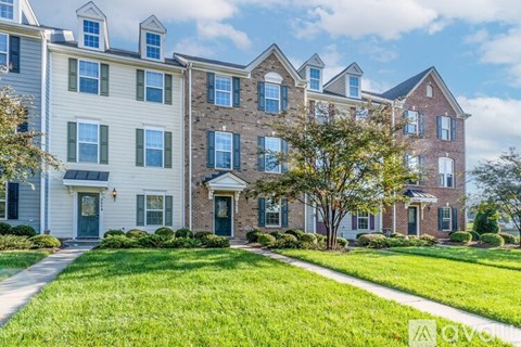 A row of townhouses with green lawns in front.