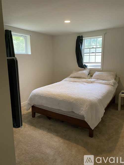 A bedroom with a bed, carpet, and a window.