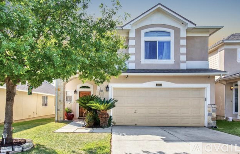 A beige house with a white garage door and a tree in front.