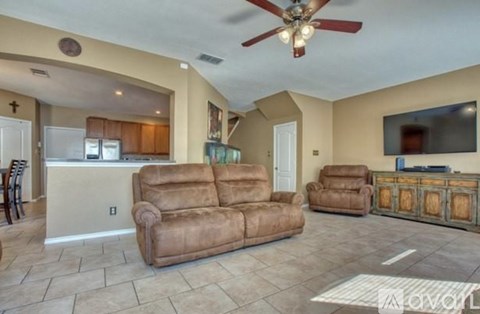 A living room with a brown couch and a ceiling fan.